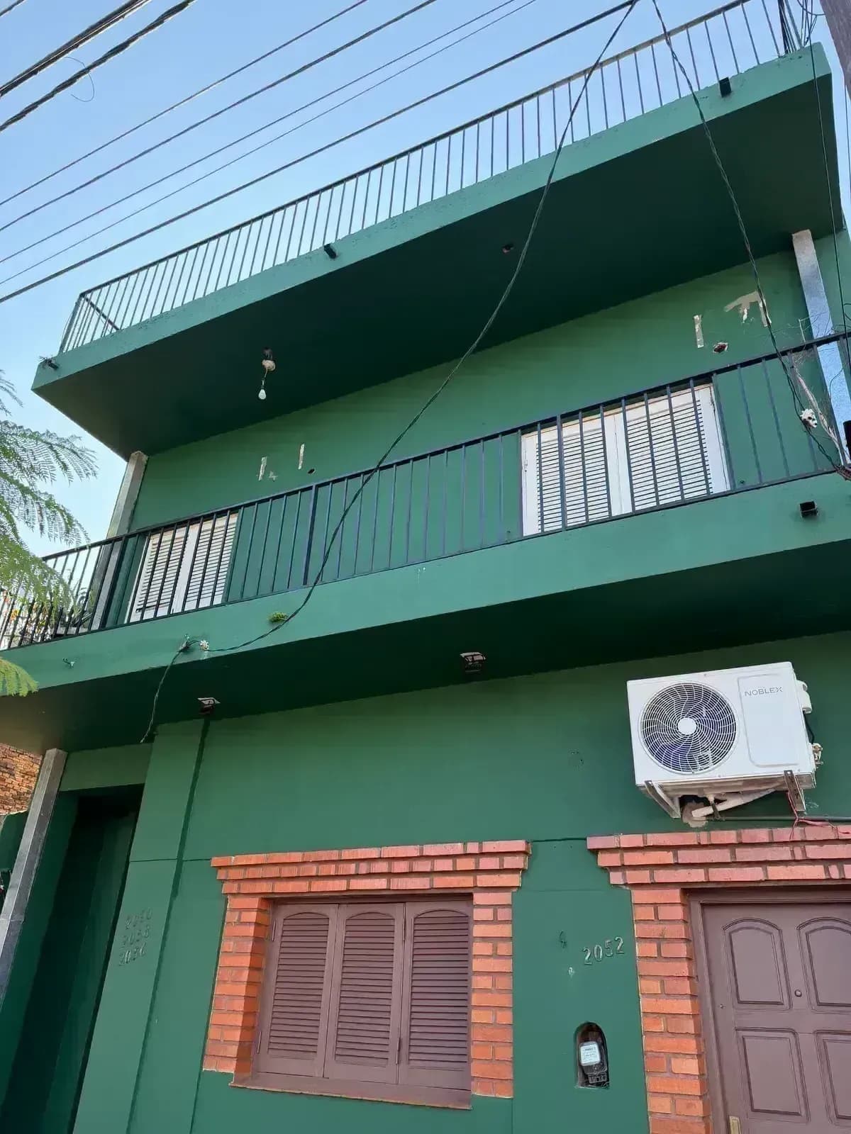 Fachada verde con detalles de ladrillo